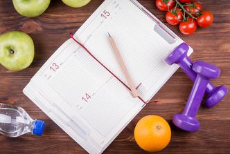 Wooden,Table,With,A,Notepad,,Pen,,Dumbbells,Bottle,Of,Water