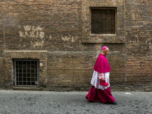 A Catholic bishop walks in a back street in Rome
