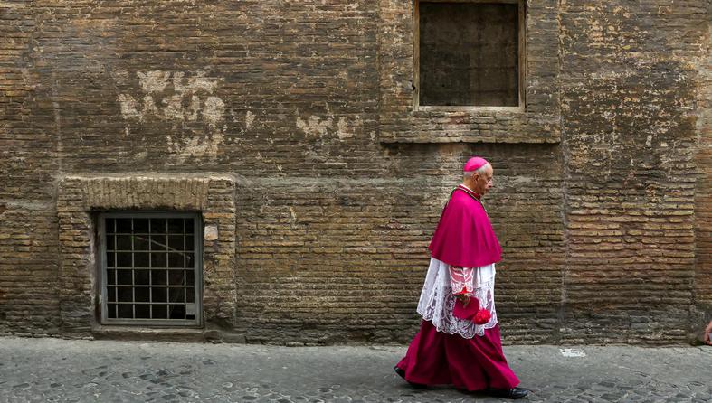 A Catholic bishop walks in a back street in Rome