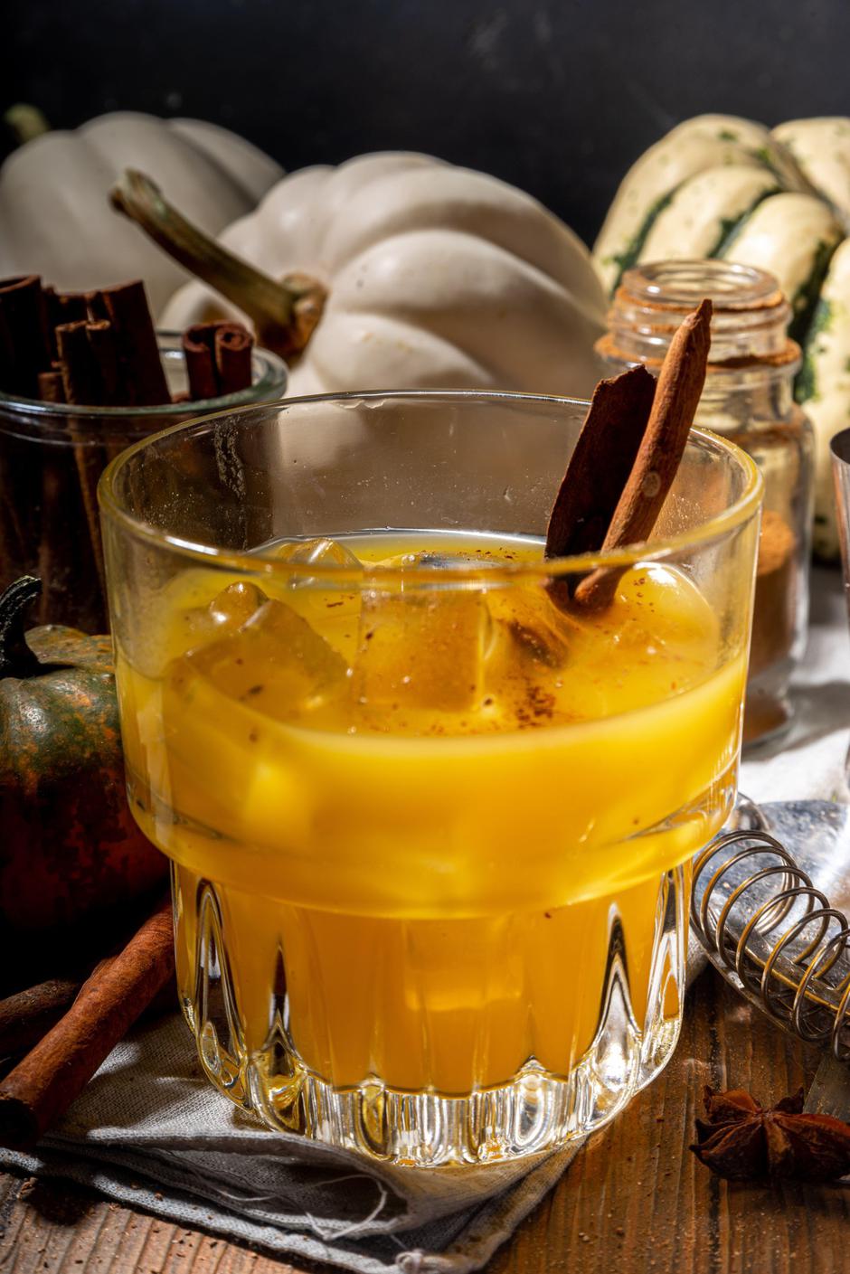 Homemade boozy pumpkin cinnamon cocktail, Refreshing iced pumpkin spice old fashioned cocktail, wooden kitchen table background copy space | Author: Profimedia