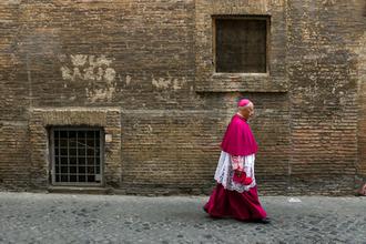 A Catholic bishop walks in a back street in Rome