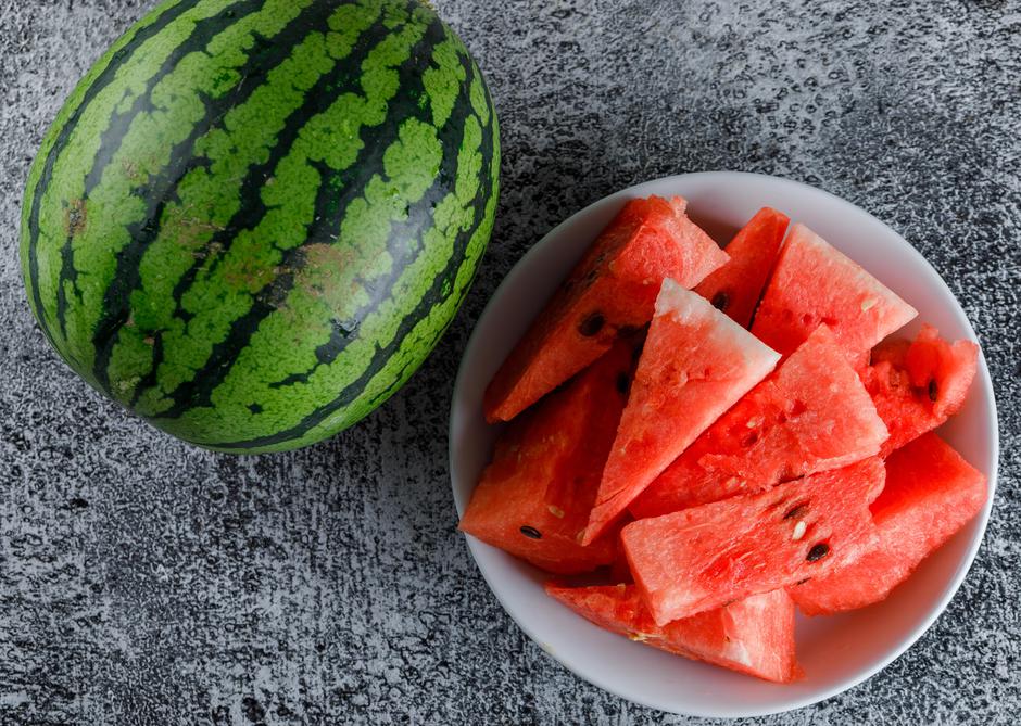 Watermelon with slices on grey grunge background, flat lay. | Author: 8photo / Freepik